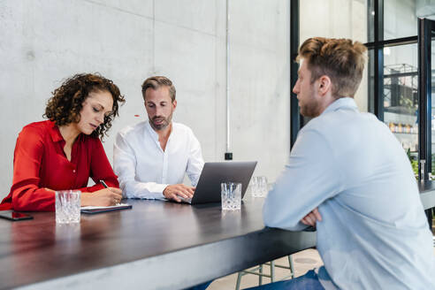 Personalverantwortlicher schreibt in Papier, während er ein Vorstellungsgespräch mit einem Bewerber im Büro führt - DIGF16845