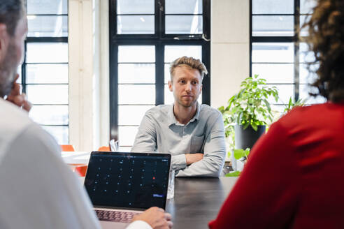 Junger Bewerber mit verschränkten Armen bei einem Vorstellungsgespräch im Büro - DIGF16846