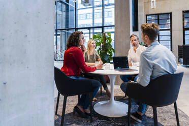 Junger Geschäftsmann im Gespräch mit Kollegen im Büro - DIGF16864