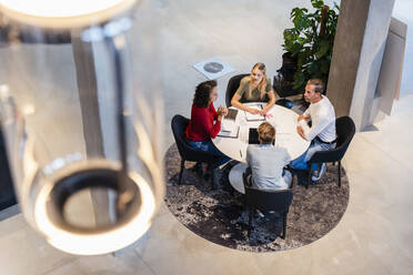 Mitarbeiter diskutieren bei der Arbeit am Schreibtisch in der Lobby - DIGF16880