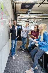 Geschäftsmann erklärt Kollegen über Whiteboard im Büro - DIGF16886