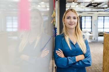 Young blond businesswoman with arms crossed at whiteboard - DIGF16900