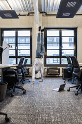 Geschäftsmann übt Handstand am Arbeitsplatz - DIGF16906