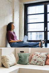 Thoughtful businesswoman with laptop in office - DIGF16909