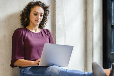 Unternehmerin mit Laptop bei der Arbeit im Büro - DIGF16912