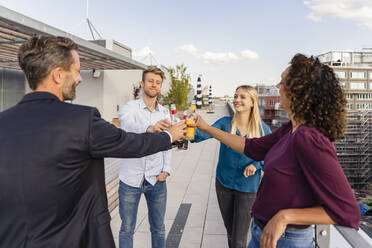 Happy coworkers toasting drink bottles on rooftop - DIGF16930