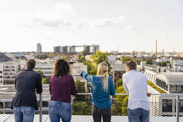 Mitarbeiter schauen auf das Stadtbild, während sie auf dem Dach stehen - DIGF16931