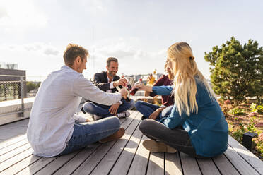 Mitarbeiter stoßen auf der Dachterrasse mit Getränken an - DIGF16937