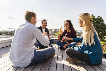 Fröhliche Kollegen stoßen auf der Dachterrasse mit Getränken an - DIGF16938