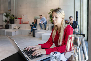 Blonde Geschäftsfrau mit Laptop am Schreibtisch - DIGF16946