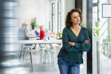 Thoughtful businesswoman with arms crossed in office - DIGF16961