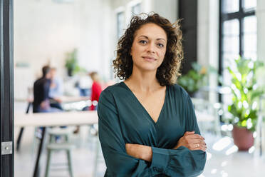 Businesswoman with arms crossed standing in office - DIGF16962