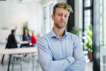 Young businessman with arms crossed in office - DIGF16964