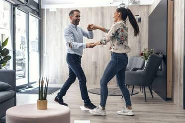 Carefree business couple dancing in office - JSRF01689