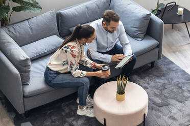 Businessman discussing over tablet computer with businesswoman on sofa - JSRF01694