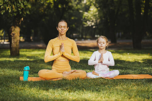 Mutter und Tochter mit verschränkten Händen beim Yoga im Park - OYF00619