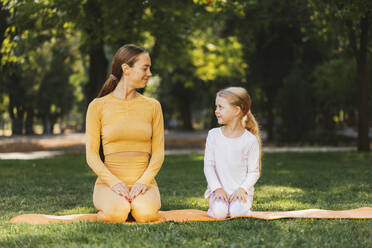 Smiling mother and daughter looking at each other in public park - OYF00621