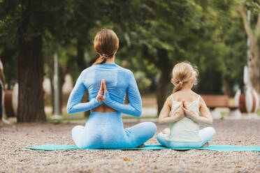 Mother and daughter with hands clasped behind back in park - OYF00635