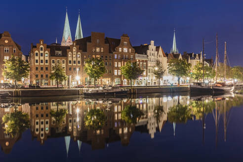 Deutschland, Schleswig-Holstein, Lübeck, Langzeitbelichtung von beleuchteten Stadthäusern, die sich im Travekanal spiegeln, bei Nacht - WDF06656