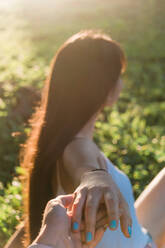 Seitenansicht eines nicht erkennbaren weiblichen Jugendlichen mit langen Haaren, der seine beste Freundin an der Hand hält, beleuchtet - ADSF31287