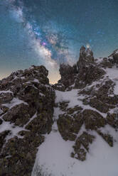 Wunderschöne Landschaft mit schroffen, felsigen, schneebedeckten Berggipfeln unter nächtlichem Sternenhimmel mit Milchstraße - ADSF31298