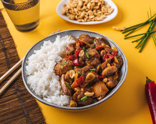 Von oben Komposition Schüssel mit Kung Pao Huhn mit weißem Reis Erdnuss und roten Chilischoten und grünen Zwiebeln und Stäbchen - ADSF31301