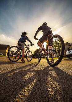 Weitwinkelaufnahme von Vater und Kind auf einer abendlichen Fahrradtour. - CAVF94943