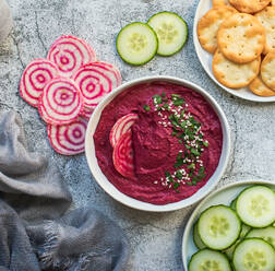 Bowl of beet hummus, vegetables and crackers on gray backgrounf. - CAVF94945