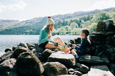 Mom cooking on a portable cooker whilst camping with her son - CAVF95003