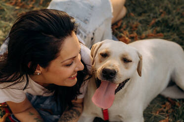 Glückliche Frau, die ihren Labradorwelpen im Freien umarmt - CAVF95046
