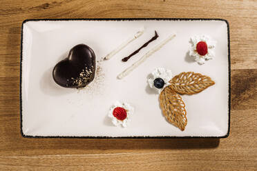 Studio shot of tray with finely presented chocolate cake with fruit and whipped cream additions - DAWF02068