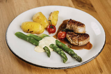 Steaks with sauce, potatoes, cooked cherry tomatoes and asparagus stalks - DAWF02072