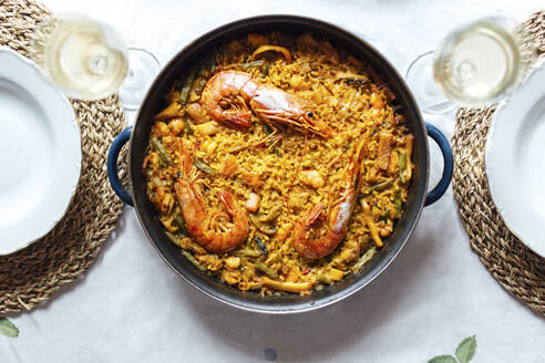 Pan of ready-to-eat paella with shrimps and two glasses of white wine - EGHF00206