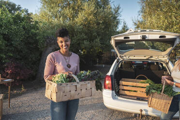 Porträt einer lächelnden Bäuerin mit Gemüsekorb im Auto - MASF26381