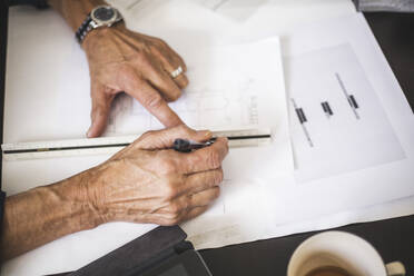 High angle view of male owner drawing line with ruler at table - MASF26466