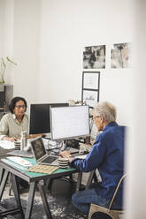 Female and male colleagues working on computer in office - MASF26475