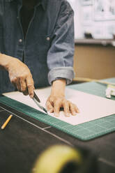 Midsection of male entrepreneur cutting paper at workshop - MASF26508