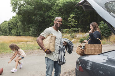 Porträt eines Mannes mit Picknickdecke und Tasche bei einer Familie - MASF26526