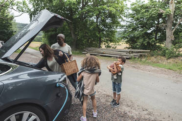 Frau beim Ausladen des Gepäcks mit Familie beim Picknick - MASF26527