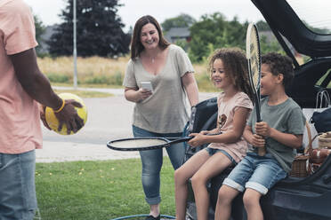 Lächelnde Eltern spielen mit Kindern im Elektroauto - MASF26556