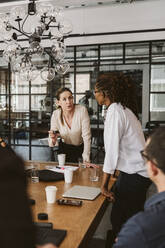 Geschäftsfrau erklärt männlichen und weiblichen Kollegen während einer Sitzung im Sitzungssaal ein Produkt - MASF26602