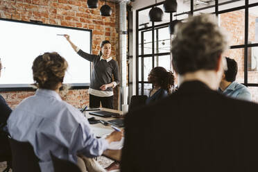 Mature businesswoman giving presentation to male and female colleagues in board room - MASF26656