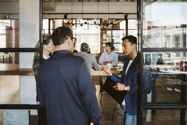 Business people discussing while standing at doorway - MASF26668