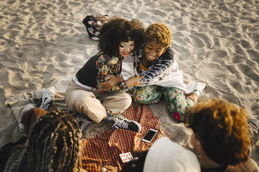 Smiling teenage girl embracing non-binary friend at beach - MASF26680