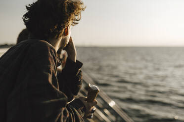 Jugendlicher mit Eiswaffel in der Hand und Blick aufs Meer - MASF26698