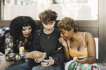Teenage boy sharing smart phone with shocked friends - MASF26723