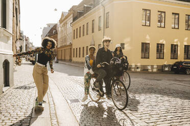 Fröhliche Freunde auf dem Fahrrad und Skateboard in der Stadt - MASF26729