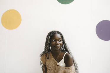Lächelnde junge Frau vor weißer Wand mit Tupfen - MASF26750