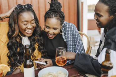 Cheerful female friends using mobile phone in party - MASF26763