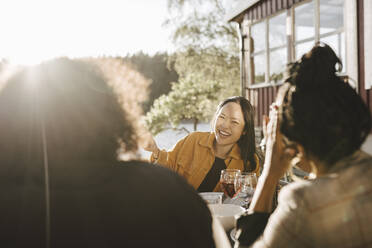 Glückliche Frau im Gespräch mit weiblichen Freunden auf einer Party an einem sonnigen Tag - MASF26789